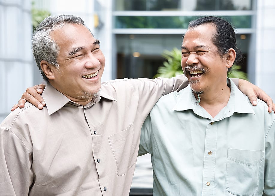 Two older male friends happy to see each other during a reunion. — 9nong // Shutterstock