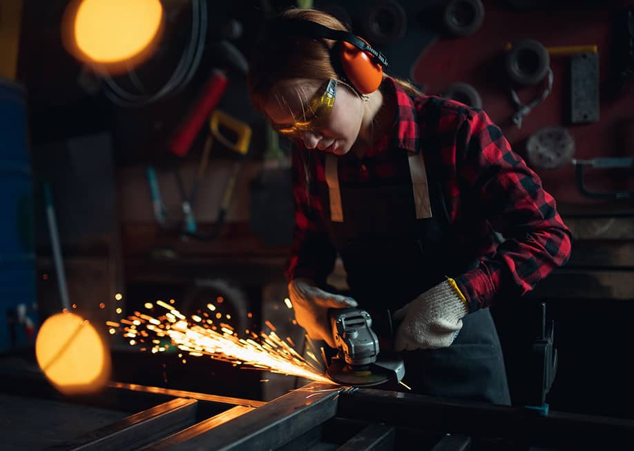 A tradeswoman working with an angle grinder. — Parilov // Shutterstock