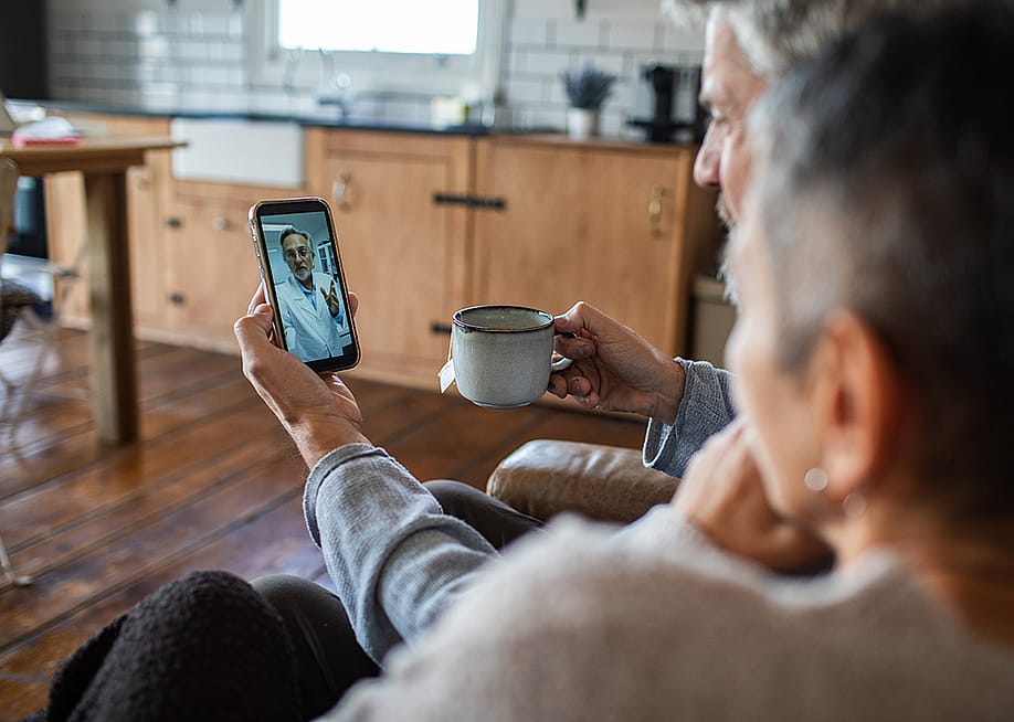 An older couple in a telehealth call at home with their doctor. — Geber86 // Shutterstock