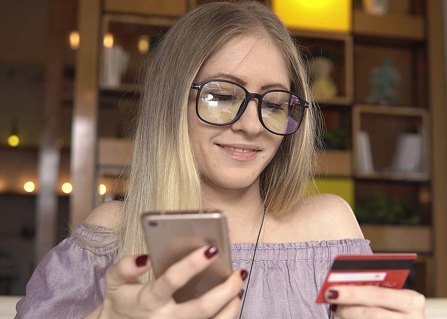 A woman shopping online using her phone and credit card. — Sergey Saulyak // Shutterstock