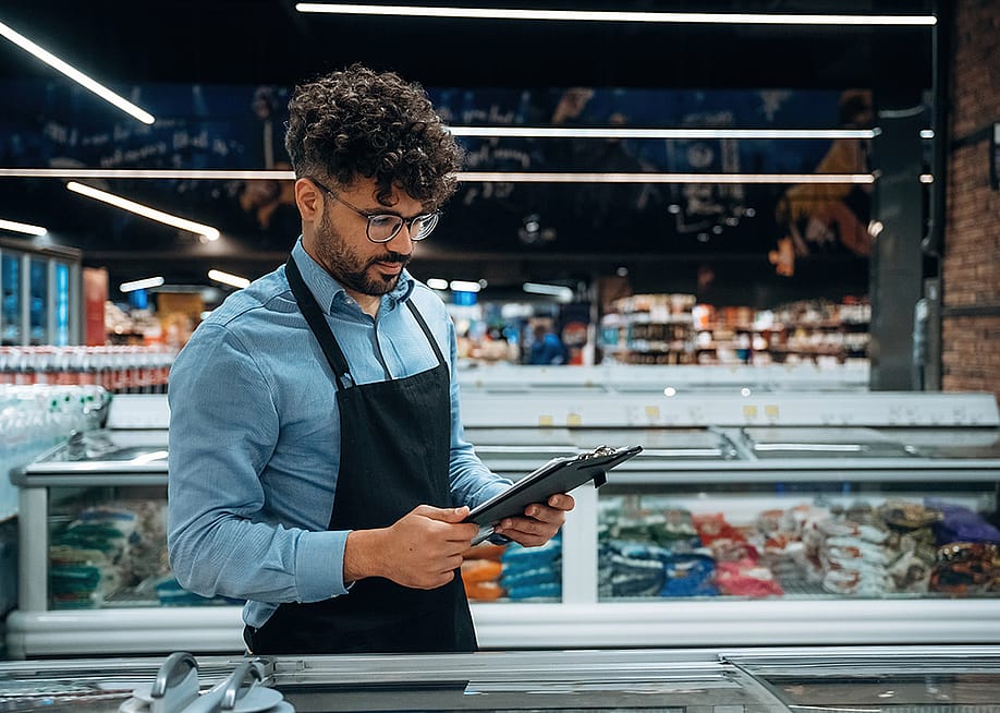 A grocery manager using a checklist for store inventory. — Standret // Shutterstock