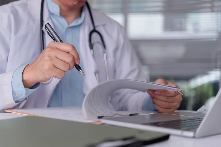 Doctor hand writing medical report on clipboard. — khunkornStudio // Shutterstock