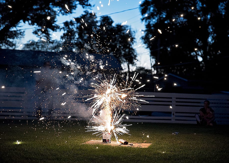 Fireworks going off at a backyard picnic during Fourth of July. — Jessica Deering // Shutterstock