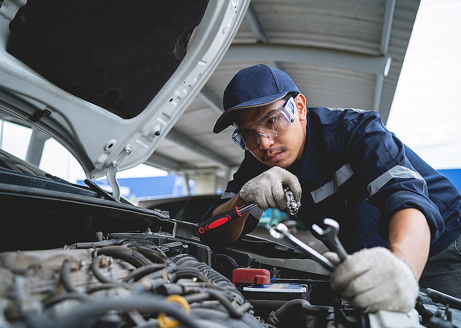 A mechanic working on a repair and service for a car engine in a garage. — KANGWANS // Shutterstock