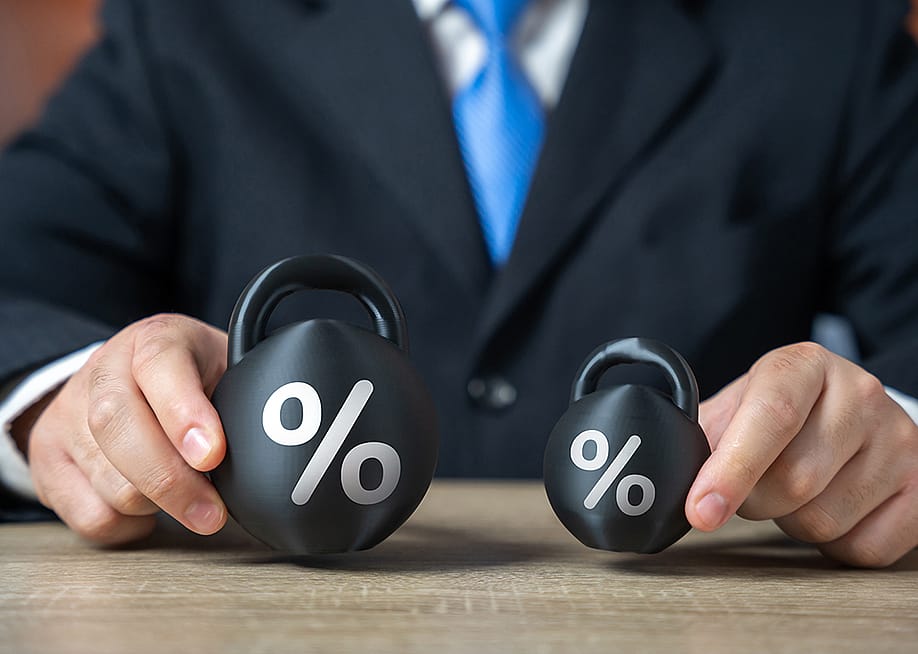 Businessman holding two weights side by side as a concept of concept of debt burden. — Andrii Yalanskyi // Shutterstock