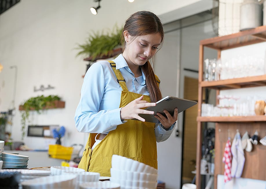 A shopkeeper checking inventory stocks of pottery and tableware from a work tablet device. — Rawpixels stock // Shutterstock