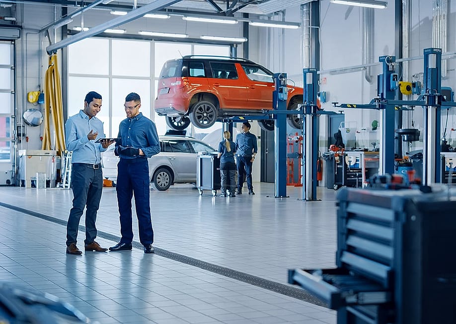 A manager explaining diagnostics results and vehicle breakdown to a mechanic in a car workshop. — Gorodenkoff // Shutterstock