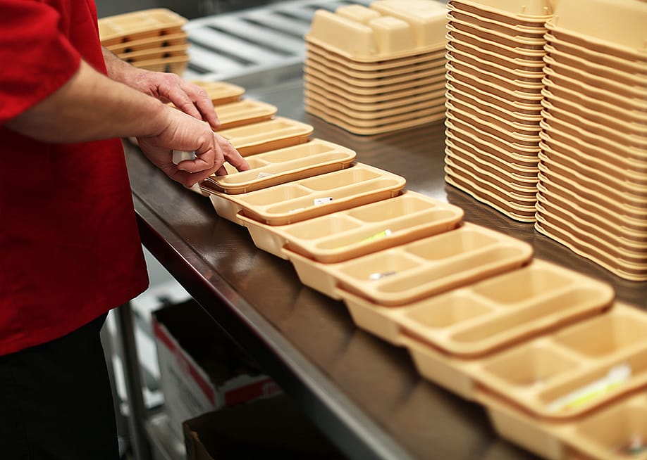 An inmate at Maine Correctional Center in Windham adds condiments to food trays in preparation for distribution throughout the facility. — Ben McCanna // Portland Press Herald via Getty Images