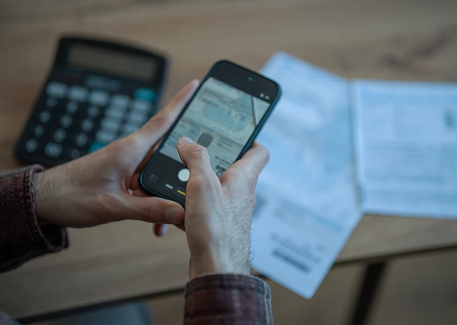 Person holding a smartphone to scan financial documents. — Anastasija Vujic // Shutterstock