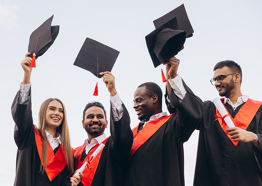 A group of graduates celebrate by holding their graduation caps in the air. — Anatoliy Cherkas // Shutterstock