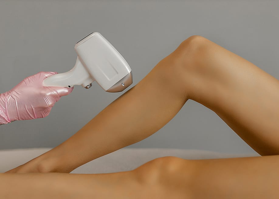 A cosmetologist doing hair laser removal to a patient's leg in a beauty salon. — Ruslan Malysh // Shutterstock