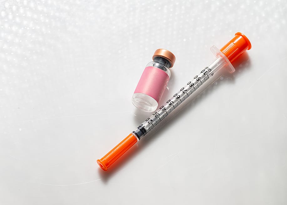 Vial of an injectable compound next to a syringe. — Anna Hoychuk // Shutterstock