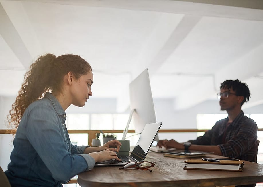 Two colleagues working at their office stations. — SeventyFour // Shutterstock
