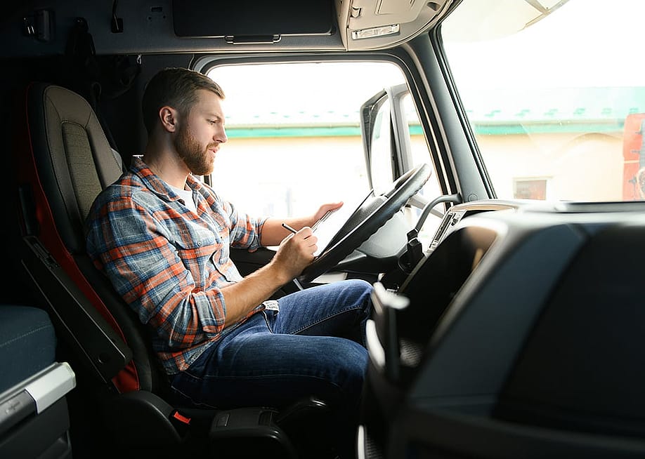 A driver checking cargo documents inside a truck before transportation. — Hryshchyshen Serhii // Shutterstock