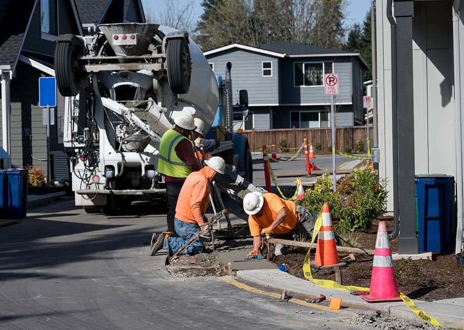 A group of construction workers smoothening a wide concrete curb. — knelson20 // Shutterstock