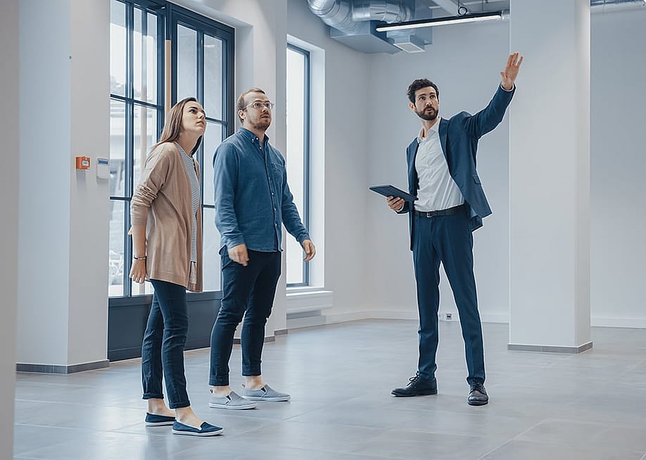 A real estate agent showing an empty office space for rent to clients. — Gorodenkoff // Shutterstock