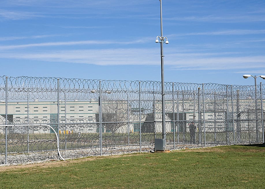A fence, barbed wire and a guard are visible at the Allan B. Polunsky Unit, the prison that houses the 169 men on Texas' death row in Livingston, Texas. — CECILE CLOCHERET // AFP via Getty Images