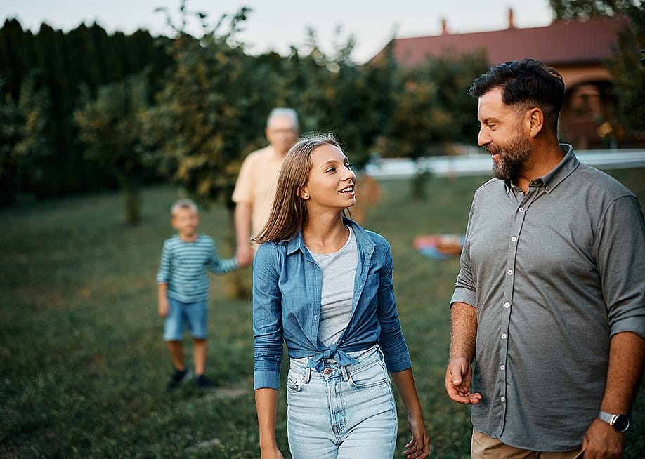 A teenager sharing stories with her father, while walking in the backyard with the family. — Drazen Zigic