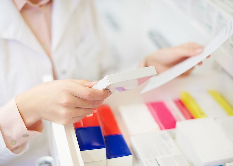 A pharmacist filling prescription at a pharmacy. — gpointstudio // Shutterstock