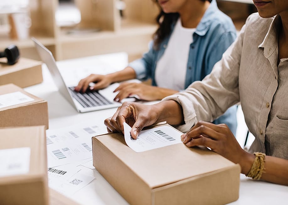 A store owner sticking a barcode label into a package box in an office warehouse. — JLco Julia Amaral // Shutterstock