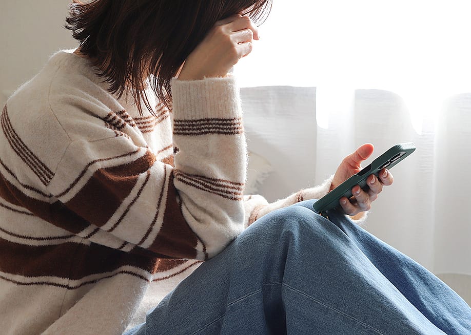 A person putting her head down while checking her smartphone. — furustic // Shutterstock