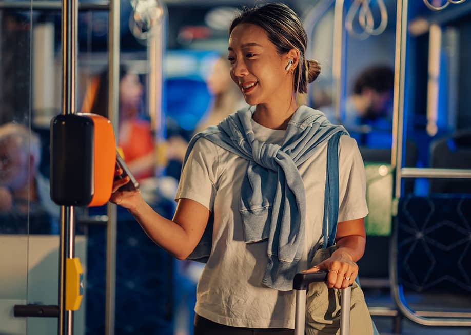 A female tourist paying for bus fare using smartphone NFC technology — Zamrznuti tonovi // Shutterstock