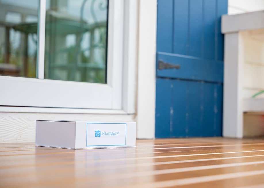 A package box labeled from pharmacy left on the front porch of a house as a delivery. — Sorapop Udomsri // Shutterstock