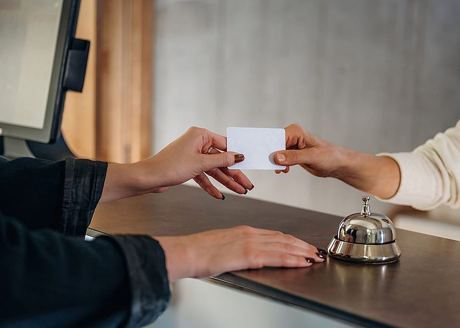A professional handing credit card over to hotel receptionist to check in. — Standret // Shutterstock