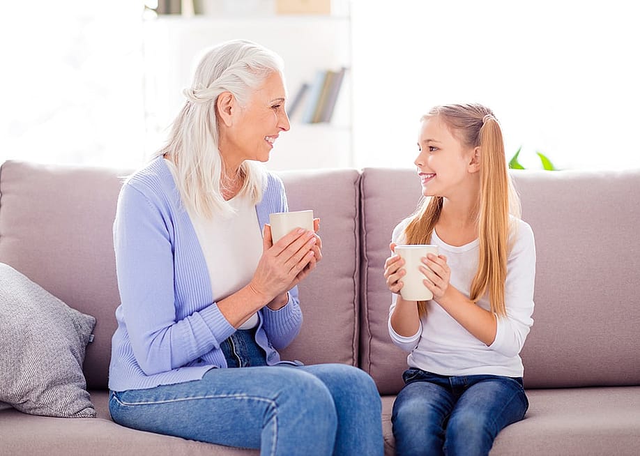 A mother and her young daughter enjoying a hot drink on the sofa. — Roman Samborskyi // Shutterstock