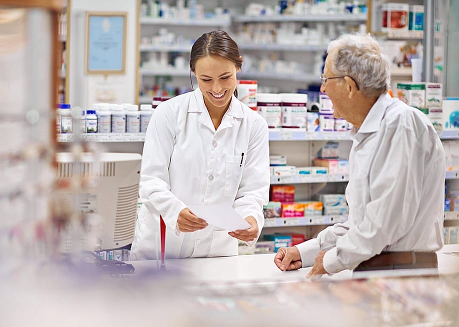 A pharmacist helping an elderly customer for prescription medicines at the counter. — PeopleImages // Shutterstock