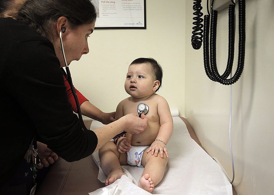 A pediatrician distracts a 9-month-old boy to check his heartbeat. — Carlos Avila Gonzalez // The San Francisco Chronicle via Getty Images
