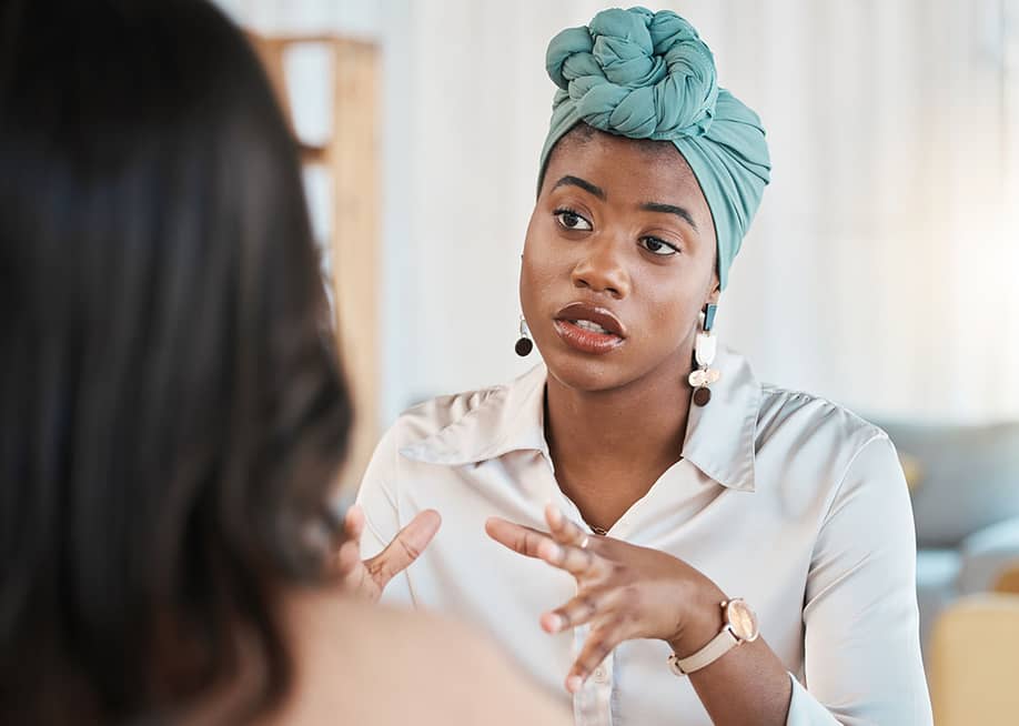 A young black female entrepreneur in discussion with a colleague. — PeopleImages // Shutterstock