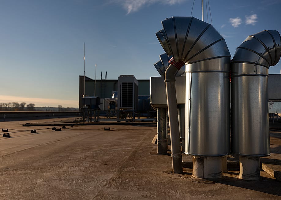 External air conditioning units and ventilation system installed on an industrial building's roof. — l i g h t p o e t // Shutterstock