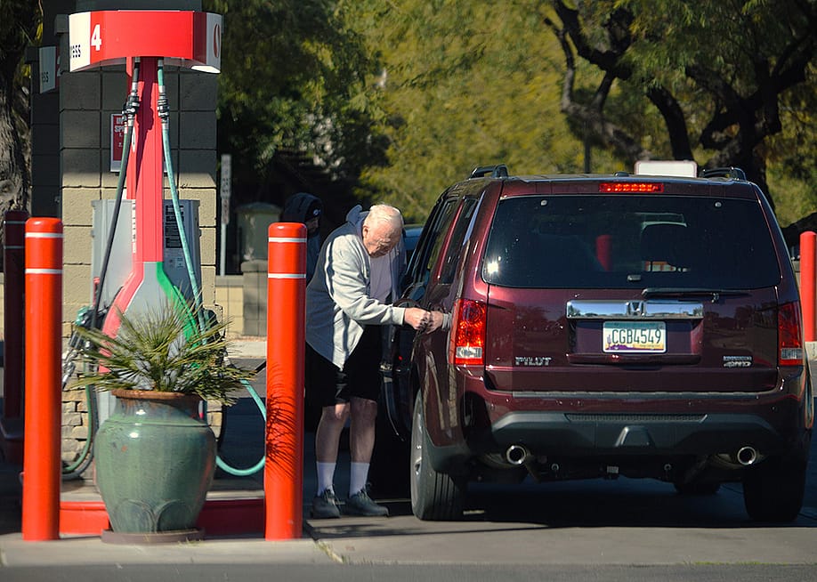 A senior citizen pumping gas into his car at a Safeway filling station in Chandler, Arizona, USA. — Around the World Photos // Shutterstock