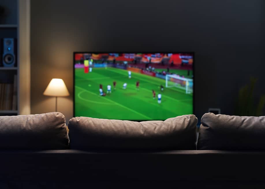 A football match displayed from a smart TV at a home's living room. — Stock-Asso // Shutterstock