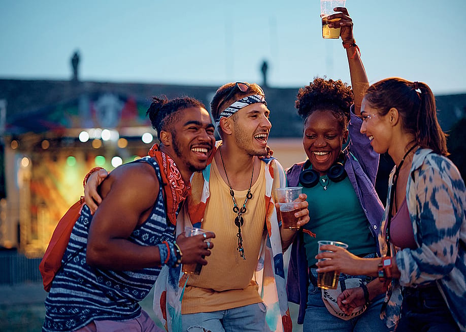 Friends enjoying and vibing to outdoors music during a summer music festival. — Drazen Zigic // Shutterstock