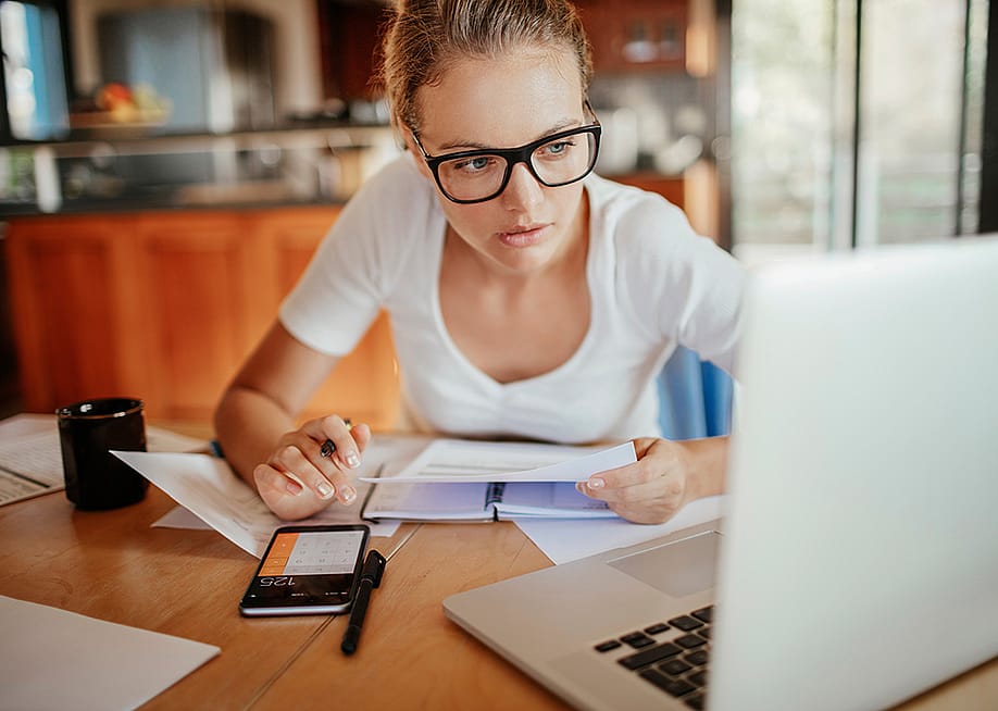 A young adult reviewing her property's documents from her laptop at home. — Geber86 // Shutterstock