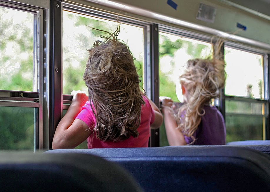 Children looking through the bus windows during a trip. — Andrea Haberichter // Shutterstock