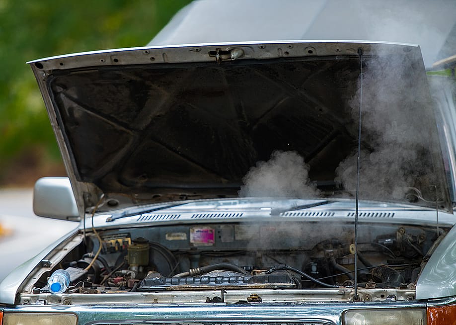 A broken car with overheating and smoking engine parked on the road. — May_Chanikran // Shutterstock