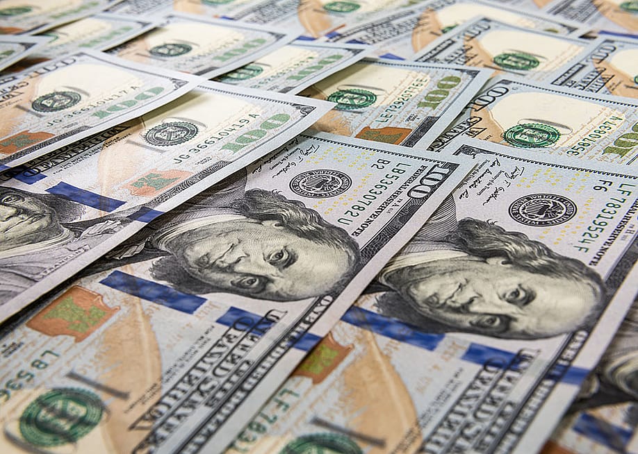 U.S. hundred dollar bills laid flat as a background. — Fitria Ramli // Shutterstock