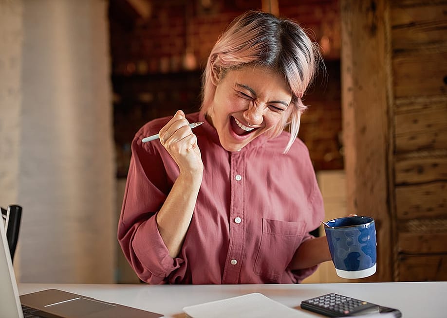 A young adult appearing to be overjoyed after finally paying off debts. — Anatoliy Karlyuk // Shutterstock