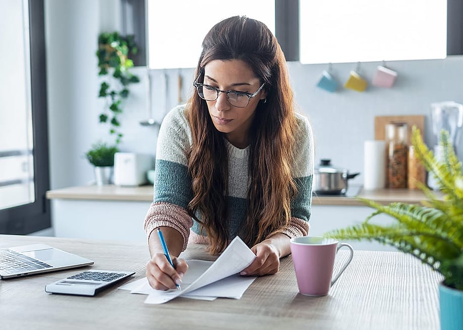 A woman reviewing finance documents at home. — Josep Suria // Shutterstock