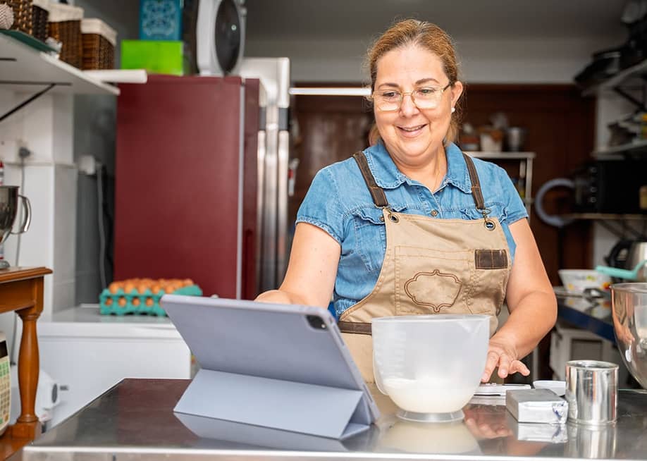 A pastry small business owner happily checking daily sales. — Guillermo Spelucin R // Shutterstock