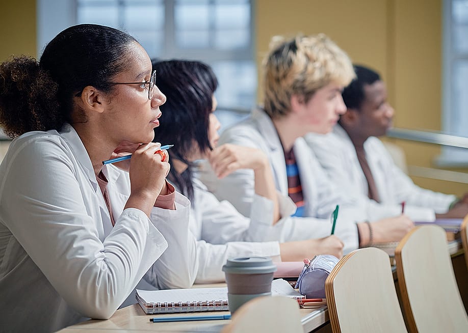 A class of medical students attentively listening to a lecture. — SeventyFour // Shutterstock