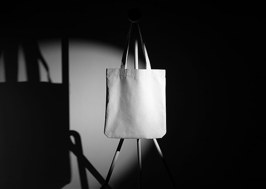 A mockup template of a tote bag on a metal hanger taken in a photo studio. — Mockup Cloud // Shutterstock