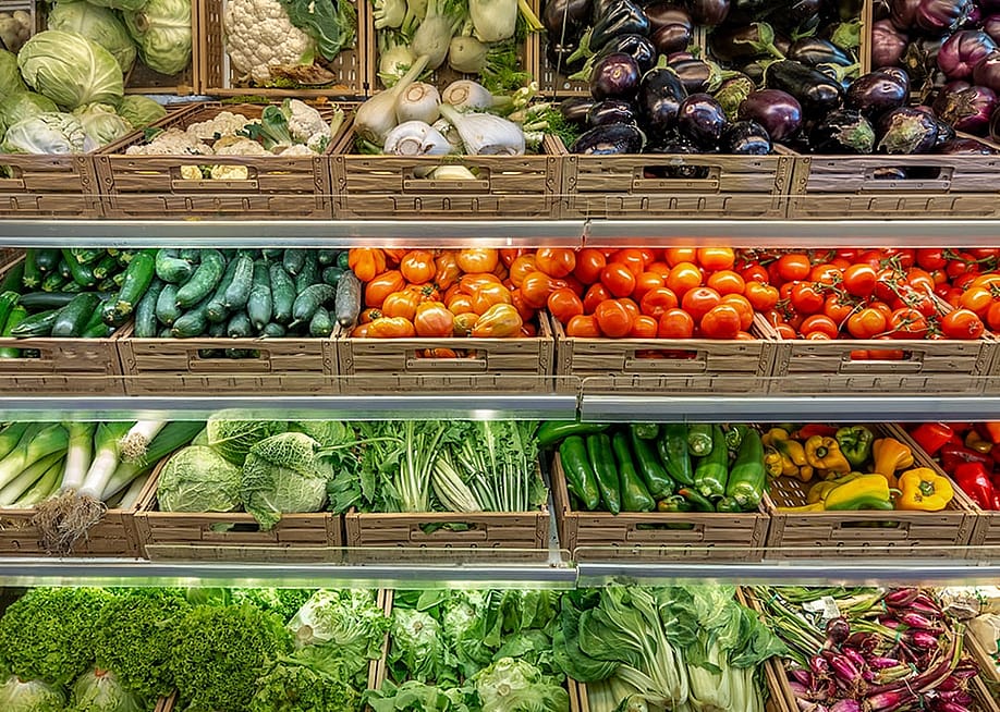 Various kinds of vegetables displayed on boxes in a greengrocer's shop. — Framarzo // Shutterstock