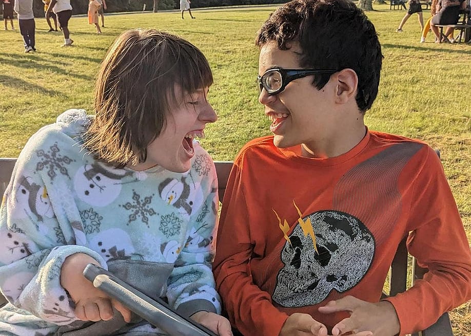 Two young individuals with disabilities happily engaging in a conversation outdoors. — Shrub Oak International School