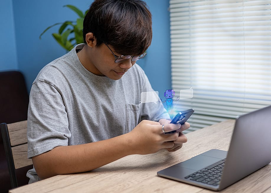 A teenage boy using smartphone at home illustrated with an AI chatbot graphic. — Kplandee // Shutterstock