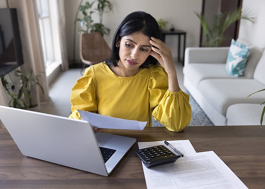 A young adult looking stressed during a personal finance review at home. — fizkes // Shutterstock