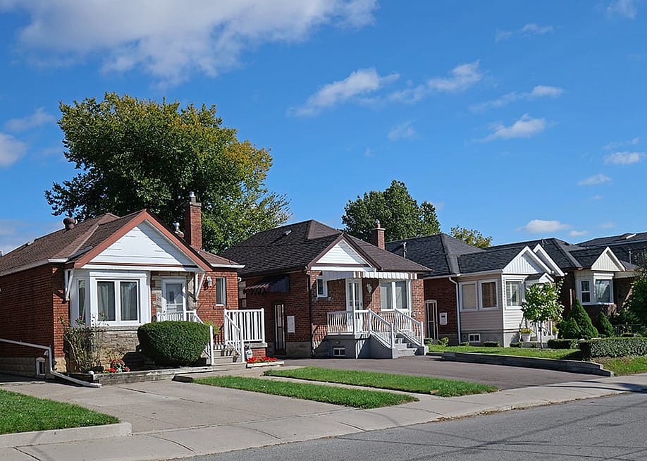 A row of detached bungalow-style brick homes in a street. — Spiroview Inc // Shutterstock